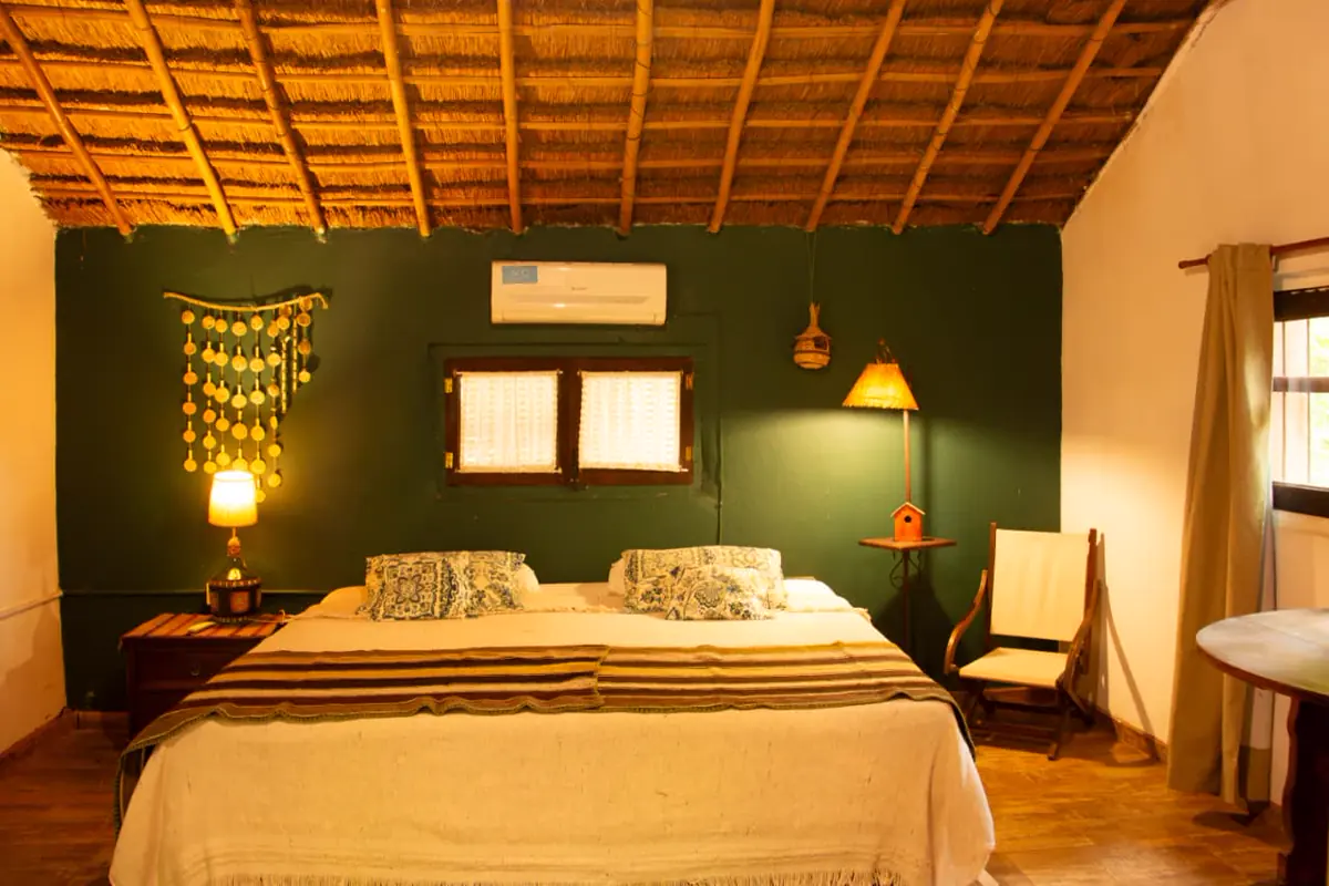 Habitación matrimonial con pared verde, techo de paja y lámparas de mesa