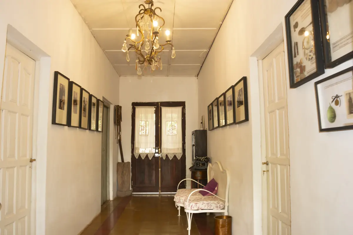 Pasillo con arañas de cristal y cuadros hacia las puertas del patio